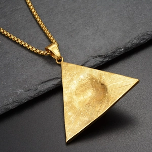 Vue détaillée du pendentif pyramide dorée aux rayons de soleil sur ardoise sombre