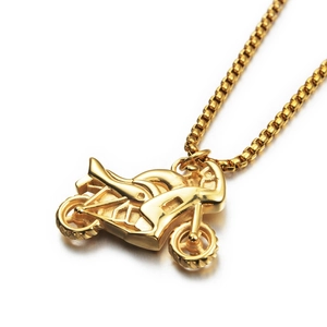 Détail d'un pendentif motocross doré avec finition texturée et chaîne box classique