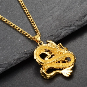 Close-up of golden Chinese dragon pendant on Cuban chain over natural gray rock