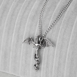 Macro detail of gothic flying dragon wrapped around a silver sword pendant necklace