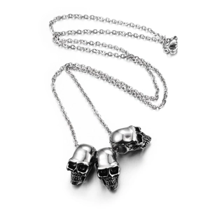 Hip hop style stainless steel necklace with three detailed skull pendants on white background