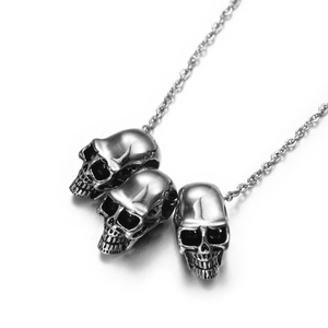 Detailed macro view of three vintage silver skull pendants on a stainless steel chain