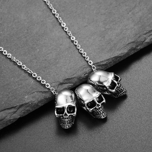 Macro shot of three polished stainless steel skulls on a rock background detail