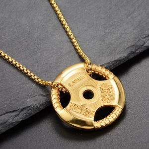 Vue macro du pendentif haltère doré avec texte motivant gravé en acier inoxydable durable