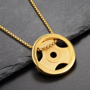Gros plan du collier disque d'haltère doré sur une surface en pierre texturée foncée