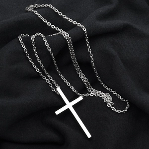 Détail macro du pendentif croix en acier poli sur un fond en tricot noir élégant