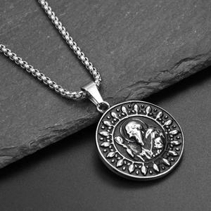 Detailed macro view of an embossed vintage religious saint pendant on a steel chain