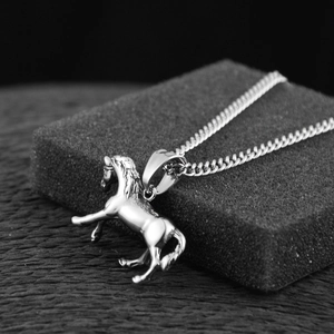 Dettaglio macro di un ciondolo a forma di cavallo in argento con catena cubana