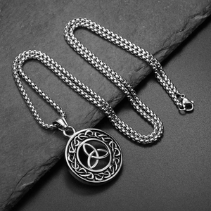 Macro shot of stainless steel Celtic Triquetra knot pendant with box chain on slate