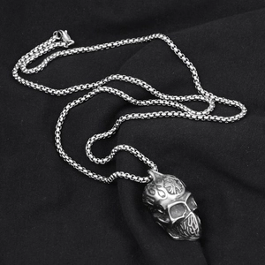 Vue macro d'un pendentif tête de mort gothique avec motif de croix sur fond sombre