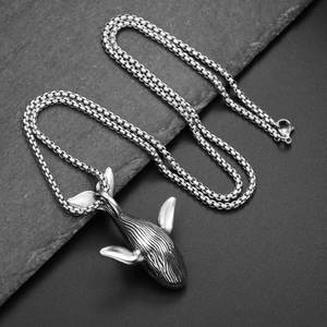 Minimalistische walvis hanger ketting van zilver rvs op zwarte stenen achtergrond