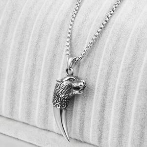Gros plan d'un pendentif tête de loup argenté avec gravures sur une chaîne à mailles