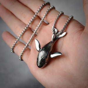 Detailopname van een walvis-hanger met fijne texturen aan een ronde kogelketting