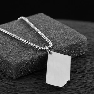 Macro shot of silver titanium steel rectangle pendant with unique cutout map details