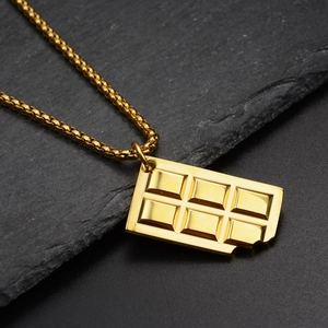 Detailed macro view of a gold-plated chocolate bar pendant with bitten corner on slate