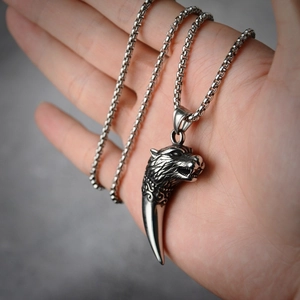 Détail macro du pendentif tête de loup en argent avec dent gravée sur chaîne box