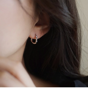 Primer plano de pendientes minimalistas de plata con diseño de gota retorcida