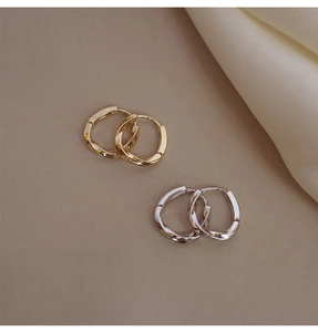 Detalle de los pendientes de aro retorcidos en color oro y plata sobre seda