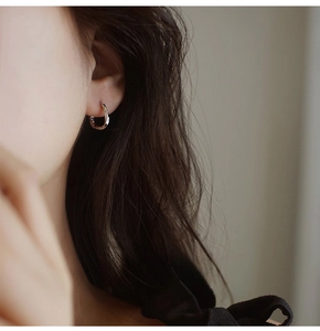 Primer plano de un elegante pendiente de aro plateado trenzado en una modelo de pelo oscuro
