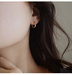 Primer plano de pendientes de aro dorados minimalistas lucidos por una modelo con elegancia