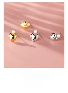 Close-up of heart-shaped pearl earrings on a textured pink leather surface