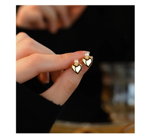 Macro shot of elegant S925 silver heart stud earrings with white pearls in gold finish