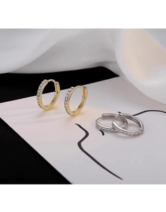 Dettaglio macro di orecchini a cerchio in oro e argento con pavé di zirconi
