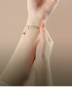 Detail of silver lily flower bracelet with green jade beads on woman's wrist