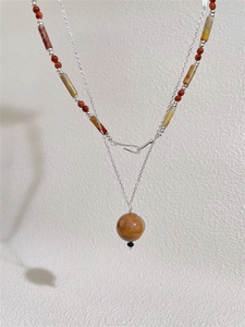 Detail einer Retro-Mehrlagige-Halskette mit braunen Perlen und Saturn-Anhänger