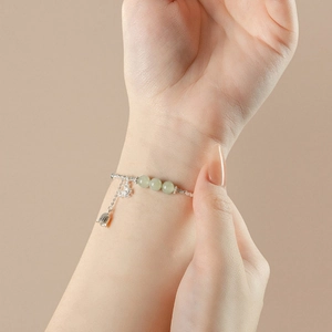 Elegant sterling silver lily of the valley bracelet with green jade beads on female wrist