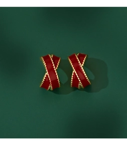 Macro shot of French vintage red enamel cross earrings with gold beaded edges