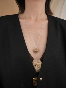 Detailansicht einer minimalistischen braunen Kugelkette an einer Silberkette