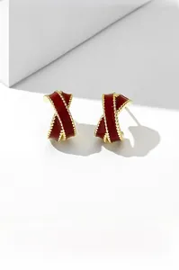Close-up of vintage French style gold earrings with red enamel and twisted ribbon design
