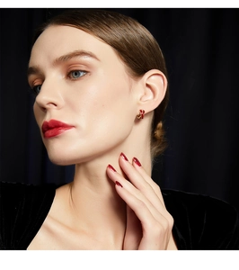 Close-up of French vintage red and gold enamel hoop earrings on a female model