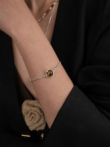 Detailaufnahme der silbernen Saturn-Halskette mit braunem Tigerauge-Stein am Model