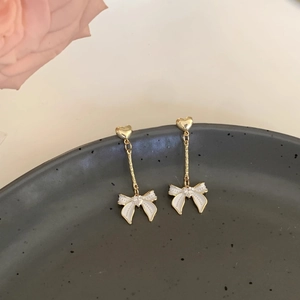 Détail de boucles d'oreilles cœur avec pendentif nœud blanc sur plat en céramique