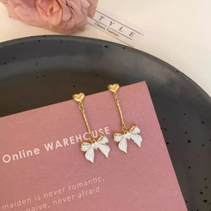 Détails des puces d'oreilles cœur doré et des pendentifs papillon en émail blanc sertis