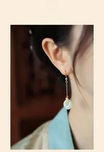 Détail de longues boucles d'oreilles chinoises en or avec bague en jade sur le modèle