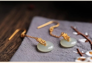 Vue macro de boucles d'oreilles chinoises avec caractère Xi doré et anneaux de jade