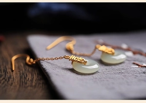 Détail macro de boucles d'oreilles chinoises dorées avec signes Xi et jade
