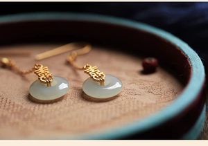 Vue macro de boucles d'oreilles Xi en or avec pendentifs Pingan Kou en jade blanc