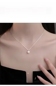 Close-up van een witte parelhanger aan een zilveren S-ketting gedragen om de hals