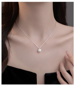 Close-up van een minimalistische ketting met een enkele parel aan een zilveren schakelketting