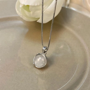Detail of moonstone pendant necklace with silver box chain on ceramic plate