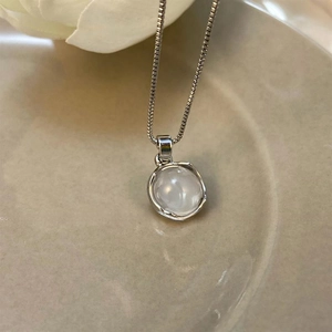 Macro detail of moonstone pendant necklace featuring polished silver bezel on fine box chain