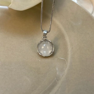 Close-up of minimalist moonstone pendant necklace resting on a ceramic dish