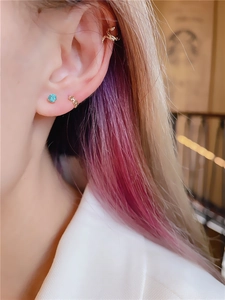 Detail of a snake-shaped ear cuff and blue gemstone stud on a female ear model