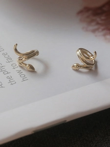 Detailed close-up of golden snake-shaped earrings with polished finish and intricate head design