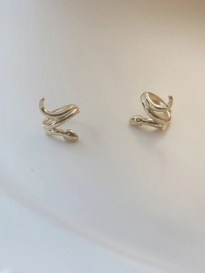 Detailed macro shot of golden snake hoop earrings with polished metallic surface finish