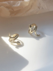 Detailed close-up of golden snake-shaped spiral earrings with elegant artistic shadows